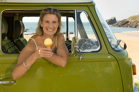 一名女性坐在露营车里手里拿着冰淇淋