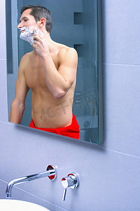 一名男子在镜子前刮胡子