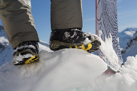 冬季雪地靴摄影照片_滑雪板运动员的脚和滑雪板