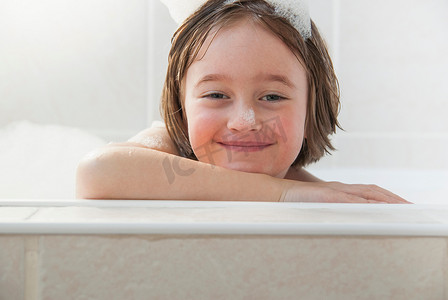 回弹海绵摄影照片_微笑的女孩坐在浴缸里
