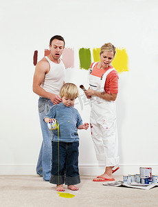 家庭避震摄影照片_蹒跚学步的男孩把油漆倒在地毯上