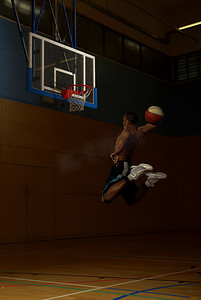 篮球场摄影照片_篮球运动员在球门篮下跳跃