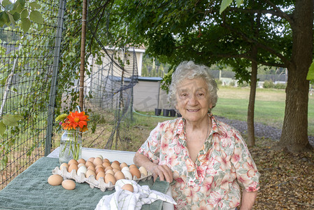 农名摄影照片_农场里一位老妇人在一盘鸡蛋旁摆姿势