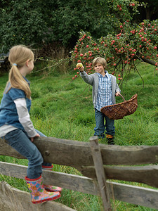 男孩在栅栏上向女孩展示苹果