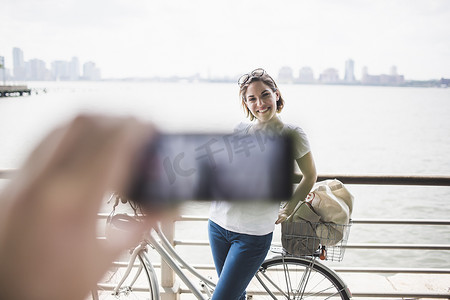 美国纽约市河畔男性用智能手机拍女友的照片