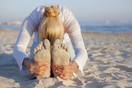 一名女子在海滩上伸展身体做瑜伽祈祷