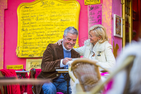 路边咖啡厅摄影照片_西班牙马略卡岛一对成年夫妇在五颜六色的路边咖啡馆里喝咖啡