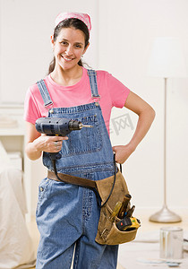 装修电钻摄影照片_在家中使用电动工具的妇女
