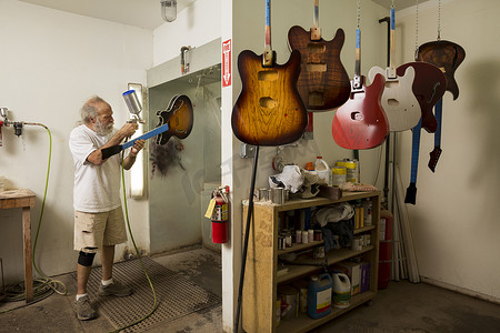 手艺人摄影照片_车间里的吉他制造者使用喷枪给吉他上漆
