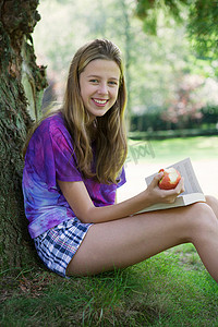 女孩在公园里吃苹果和看书