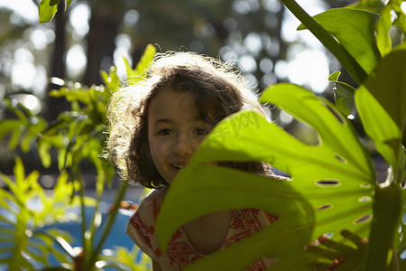 年轻的女孩微笑着站在树叶之间