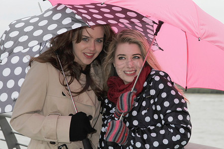 少女撑着雨伞摄影照片_两名撑着雨伞的年轻女子