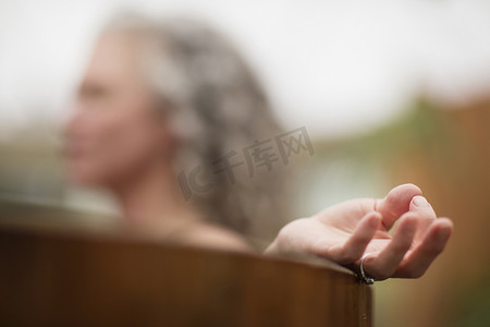 旅游活动中摄影照片_在生态静修中成熟女性的手在热水浴缸里冥想