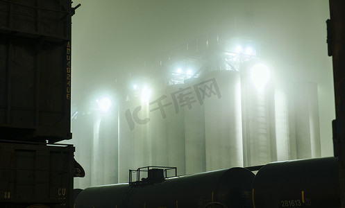 商务背景大气摄影照片_美国华盛顿州西雅图夜间火车头之间工业储罐的迷雾景象