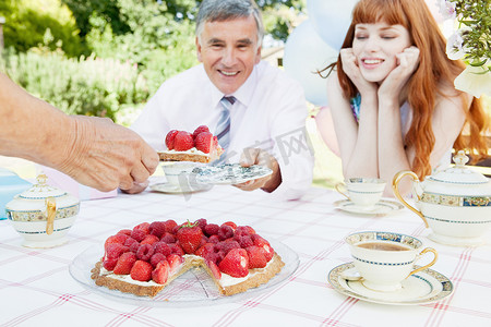 草莓馅饼摄影照片_女人向成熟的男人献上蛋糕