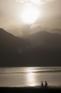 日落时分尼泊尔骑自行车观赏山湖的骑车人的剪影