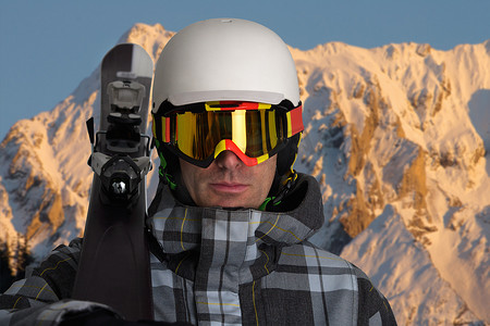 游戏雪山背景摄影照片_一名男子在雪山中抬着滑雪板