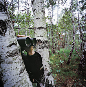 太空植物摄影照片_一名男子在森林中的一棵树后偷看