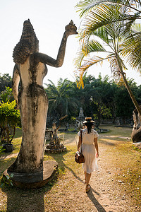 一名妇女走过老挝万象的仙湖雕像