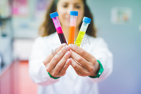 女科学家手持三种不同荧光染料的溶液