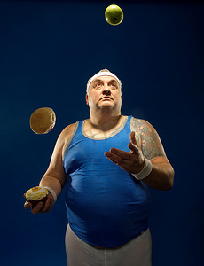 蓝色运动服摄影照片_体格高大的运动员一边吃一边杂耍