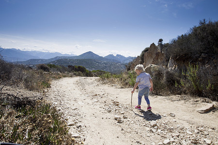 法国民族摄影照片_拿着拐杖在土路上蹒跚学步的女性卡尔维法国科西嘉岛