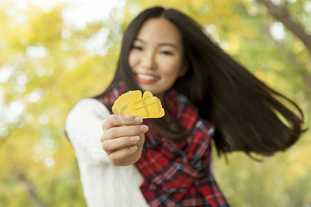 北京秋季公园年轻女子手持黄色银杏叶肖像中国