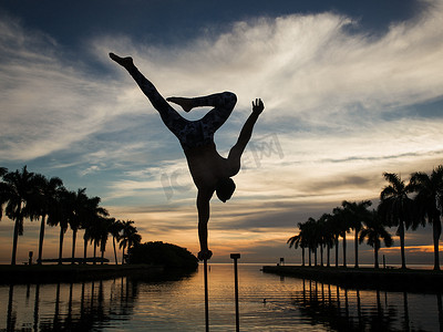 美国佛罗里达州迈阿密南角公园黄昏时分成年男子在水中用杆子保持平衡