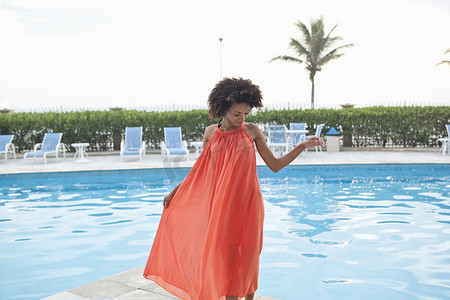 巴西里约热内卢一名年轻女子在酒店泳池边穿着橙色连衣裙