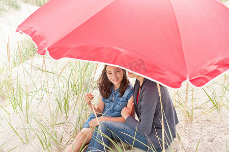 孩子伞摄影照片_在海滩伞下的母女俩