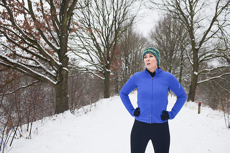 女慢跑者在白雪覆盖的场景中休息