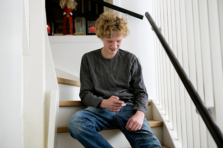 十几岁的男孩在楼梯上使用手机