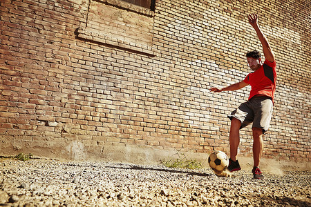 游戏红砖墙摄影照片_一位年轻人在荒地上踢足球