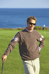 戴着墨镜的高尔夫球手靠在高尔夫球杆上手放在臀部看着摄像机