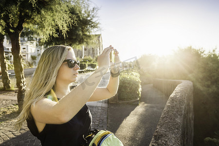 拍照旅游景点摄影照片_用智能手机拍照的年轻女子法国比亚里茨
