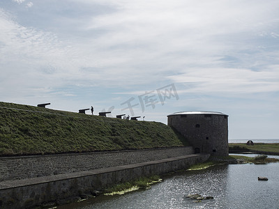 旅游活动中摄影照片_瑞典奥兰德防御墙上的一排剪影大炮
