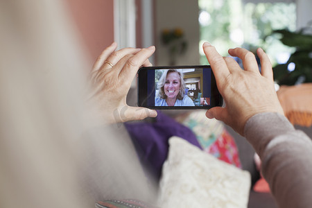 手持智能手机的资深女性与朋友进行视频通话