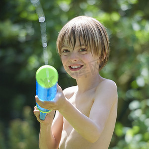 玩具水枪摄影照片_小男孩在花园里喷水枪的肖像