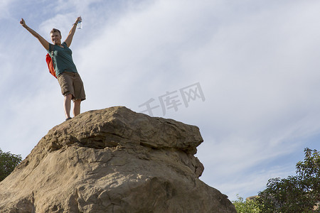 女徒步旅行者在岩石上举起手臂