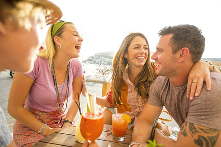 西班牙马略卡岛海滨餐厅两对成年情侣边喝鸡尾酒边大笑