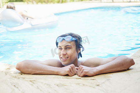 成年了摄影照片_游泳池里头发湿润面带微笑的年轻人肖像