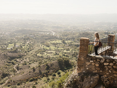 阳台植物摄影照片_站在阳台上看风景的中年妇女西班牙安达卢西亚米哈斯