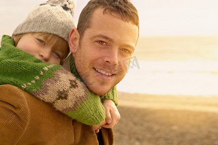 一名男子在海滩上抱着小男孩秋天