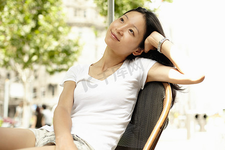 松鹤中国风名片摄影照片_上海外滩一名年轻女子用肘部支撑着抬头看着路边的咖啡馆中国