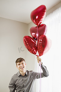 礼仪之邦摄影照片_一名年轻男子手持心形气球