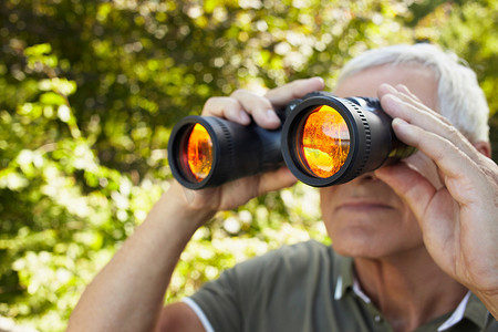 一位老人用双筒望远镜看