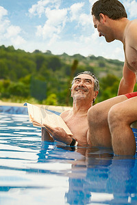两个人抬头看摄影照片_年纪较大的男子在游泳池里看新闻