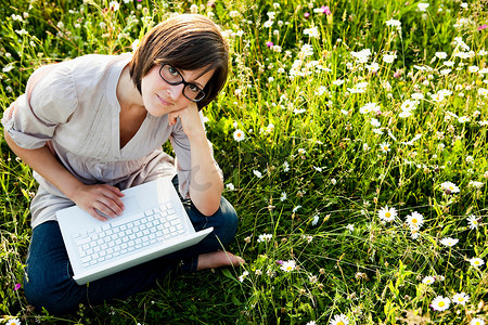 荒野草地上拿着笔记本电脑的女人