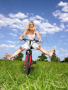 蓝天草原骑马摄影照片_在自行车上玩耍的女人