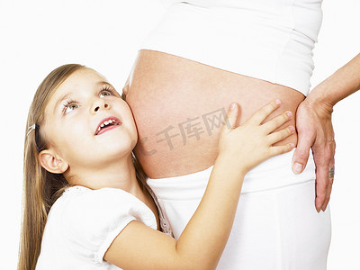 抱着母亲怀孕的肚子的女孩
